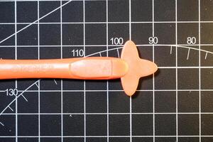Closeup Plastic opener on black striped rubber mat. Plastic opener is used to remove and disassemble model kits parts that have been installed. Plastic tools and equipment for hobbyists. photo