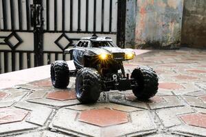 Toy car during outdoor rain with lights on. Remote Control Car being played in the yard during rain. Hobbies and Leisures. Graphic Resources. Toy Photography Concepts photo