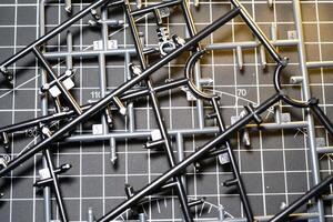 Abstract Backgrounds of Black Plastic Frame for Model Kit. Plastic model kit frame with black cutting mat background with striped pattern. Building Robot Model Kit. Toys and Hobbies photo