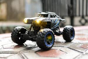 Toy car outdoor rain with lights on. Remote Control Car being played in the yard during rain. Hobbies and Leisures. Graphic Resources. Toy Photography Concepts photo