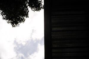 Backgrounds Split in half. One side shows a cloudy sky and the other side is covered by a roof. Low angle shot. Negative Space. photo