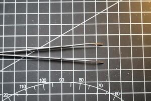 Closeup of metal precision tweezer with pointed tip. Tweezer is on a black cutting mat with lines. A tool that functions to clamp and pull out small objects. Negative Space photo
