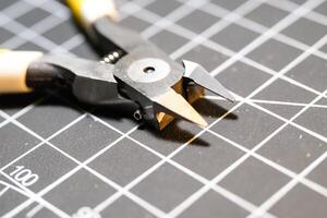 Closeup single blade nipper tools on black cutting mat. Nippers are used to cut small plastic parts. Pliers are used to cut. Model kit builder tools. Hobbies and leisures. photo