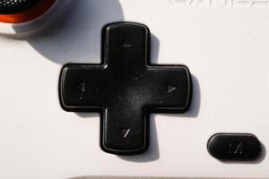Directional Pad or D pad is black on a white Game controller. Directional pad is used to move focus up, down, right, and left in the user interface. Hobbies and leisures. Negative Space photo