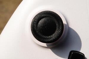 White gamepad with black joystick with rubber. The game controller buttons are set soft and ergonomic. Finger mechanics and gameplay. Hobbies and leisures. Macrophotography Theme photo