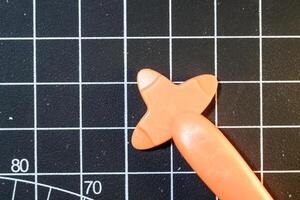 An Orange Plastic opener on black striped rubber mat. Plastic opener is used to remove and disassemble model kits parts that have been installed. Plastic tools and equipment for hobbyists. photo
