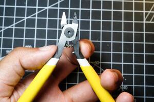 A man's hand on black cutting mat holds a nipper for cutting plastic. Black Cutting mat backgrounds with white lines. The concept of a master model kits hobby. Negative space photo