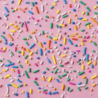Colorful sprinkles on a pink background photo