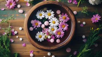 A bowl filled with flowers and pills on a wooden table photo