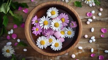 A bowl filled with flowers and pills on a wooden table photo