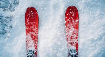Two skis are standing on top of a snow covered hill photo