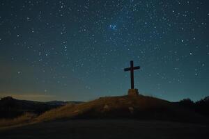 A cross stands on top of a hill with stars in the sky photo