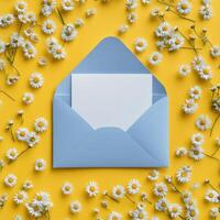Open envelope with white paper and daisies on yellow background photo