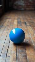 A blue ball sitting on a wooden floor photo