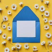 White paper and envelope with daisies on yellow background photo