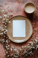 Blank paper on plate with flowers and cup of coffee on pink background photo