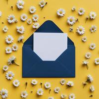 An open envelope with white paper and daisies on yellow background photo