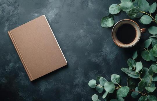 Coffee and notebook on a dark table with eucalyptus leaves photo