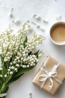 Lily of the valley flowers and gift on white background photo