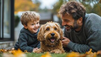 A man and boy are smiling while sitting on the grass with a dog photo
