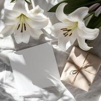 White lilies and gift box on bed with blank card photo