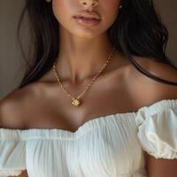 A beautiful young woman wearing a white top and gold necklace photo