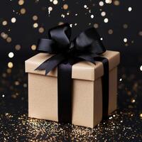 Gift box with black ribbon and gold glitter on a black background photo