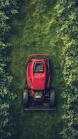 A red lawn mower is seen in the middle of a green field photo