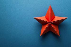 A red origami star on a blue background photo