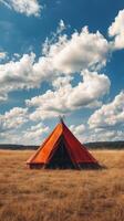 A tent is sitting in a field with a blue sky photo