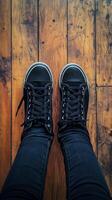 A person wearing black sneakers on a wooden floor photo