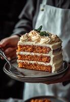 A person holding a piece of carrot cake on a plate photo