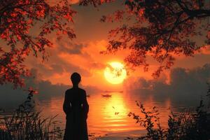 A woman stands in front of a lake at sunset photo