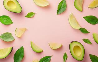 Avocado slices and leaves on a pink background photo