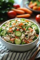 A bowl of chicken salad with carrots and cucumbers photo