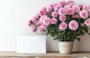 Pink flowers in a vase with blank card on wooden table photo