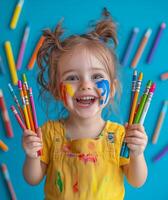 A little girl with paint on her face holding colored pencils photo