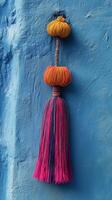 A colorful tassel hanging on a blue wall photo