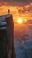 A man stands on top of a mountain at sunset photo