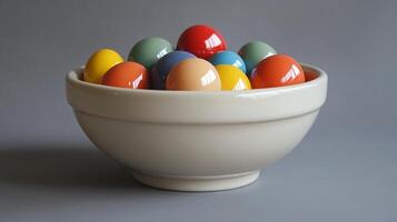 A bowl filled with colorful eggs on a gray background photo