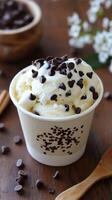 Chocolate chip ice cream in a bowl with a wooden spoon on a wooden table photo