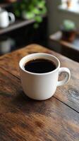 A cup of coffee sits on a wooden table photo