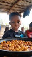 A young boy is standing in front of a pan of food photo