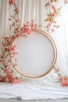 A white backdrop with pink flowers and a round frame photo