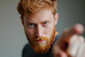 A man with a red beard pointing at the camera photo
