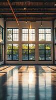 An empty warehouse with large windows and a sun shining through photo
