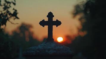 A cross is silhouetted against the setting sun photo