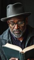 A man wearing a hat and glasses is reading a book photo