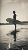 A person standing in the water holding a surfboard photo
