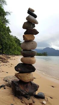 A stack of rocks on the beach near a mountain photo